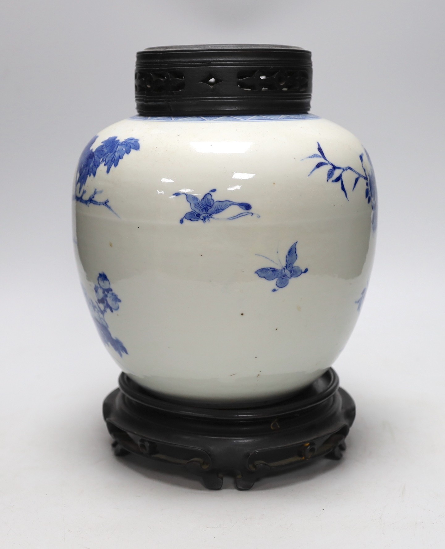 A large Chinese blue and white porcelain jar, 19th century decorated with scenes of birds amongst foliage with associated pierced hardwood cover and stand, 29cms high including stand and cover